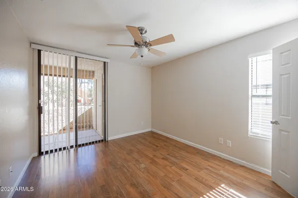 an empty room with wooden floor fan and windows