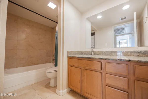 a bathroom with a granite countertop sink a toilet and shower