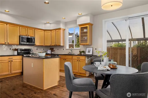a kitchen with stainless steel appliances granite countertop a stove a sink a microwave a dining table and chairs