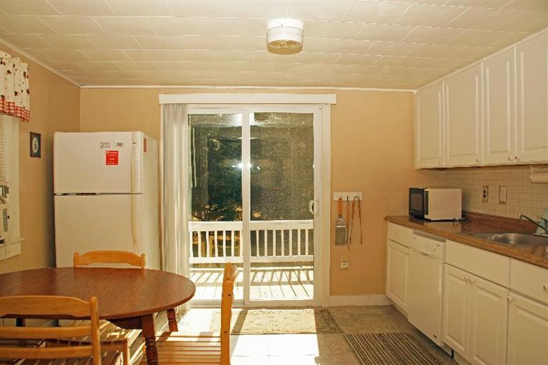 21 Gilbert Road Dennis Port, MA 02639 - Photo 14 of 18 a kitchen with a refrigerator a stove a sink and a dining table with wooden cabinet