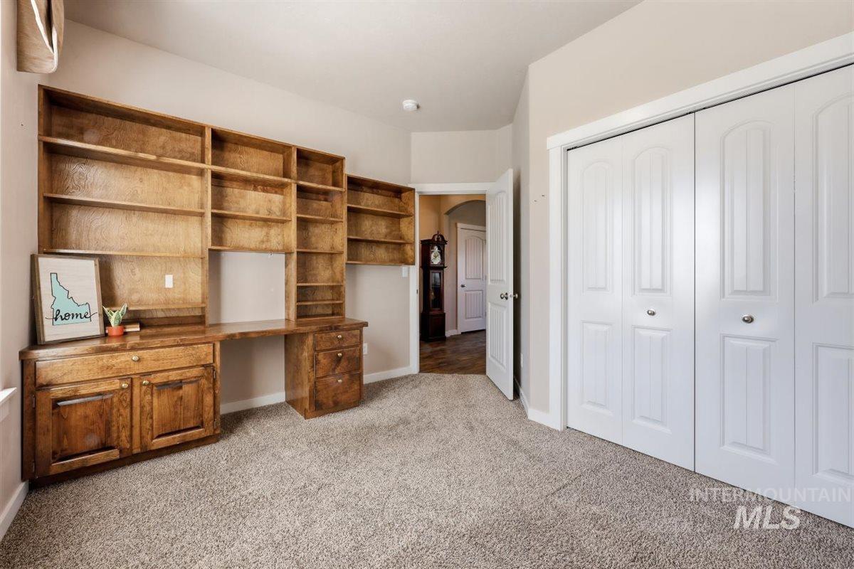 13496 Hockberger Ranch Road Caldwell, ID 83607 - Photo 8 of 40 Built-in wood cabinetry with integrated desk space and shelving, textured carpet flooring, and white bi-fold closet doors