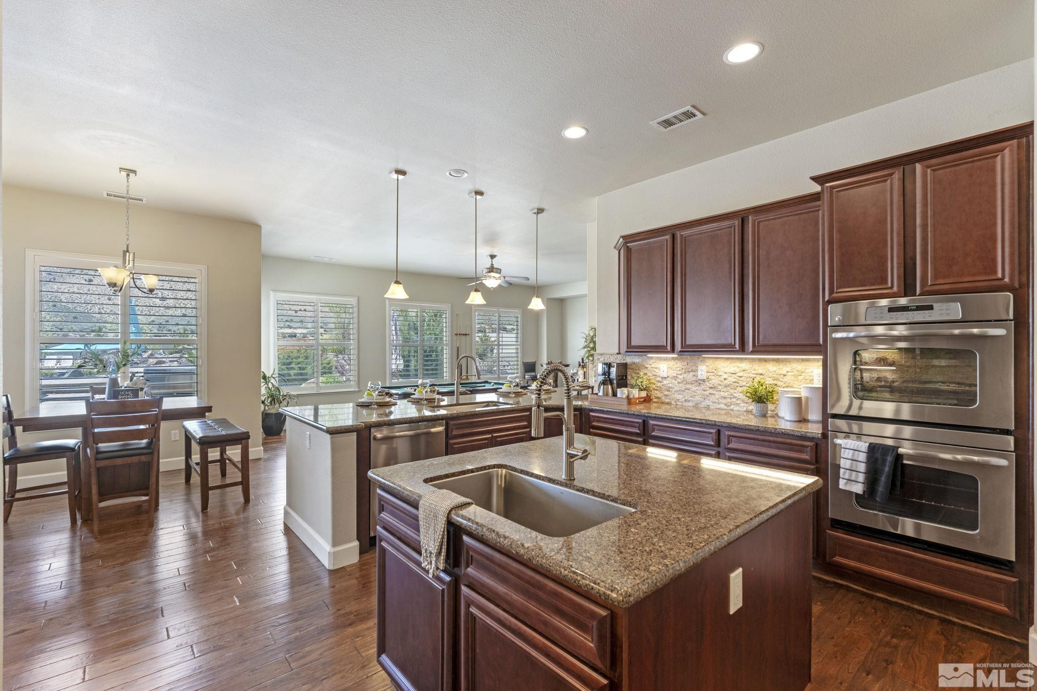 12265 Hidden Sparks, NV 89441 - Photo 16 of 39 a kitchen with stainless steel appliances granite countertop a stove top oven a sink dishwasher a dining table and chairs with wooden floor