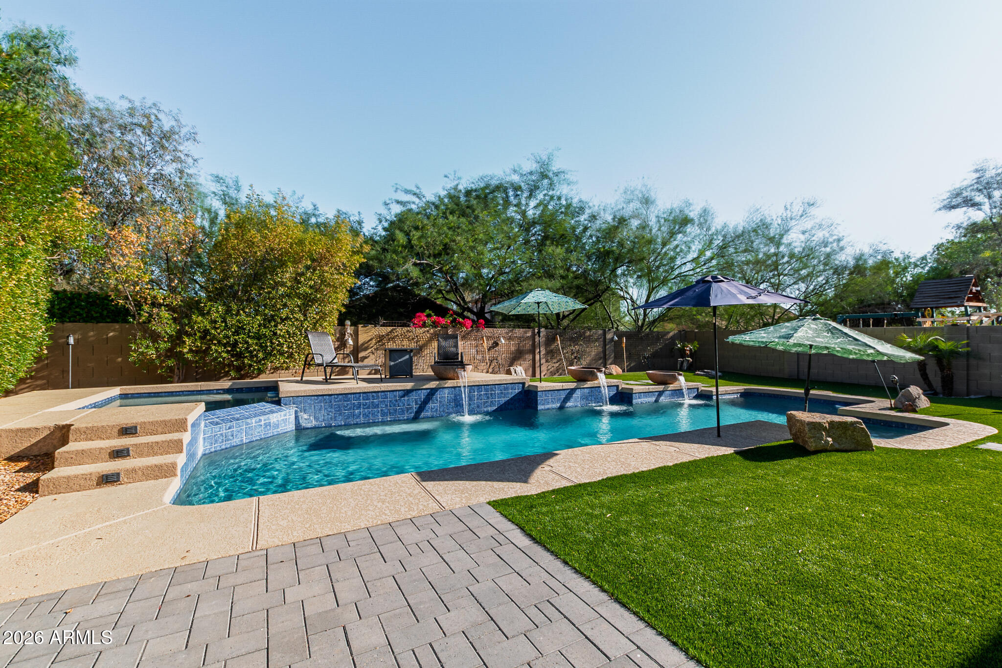 a view of a backyard with lawn chairs under an umbrella