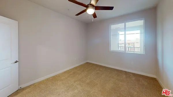 an empty room with a window and a fan