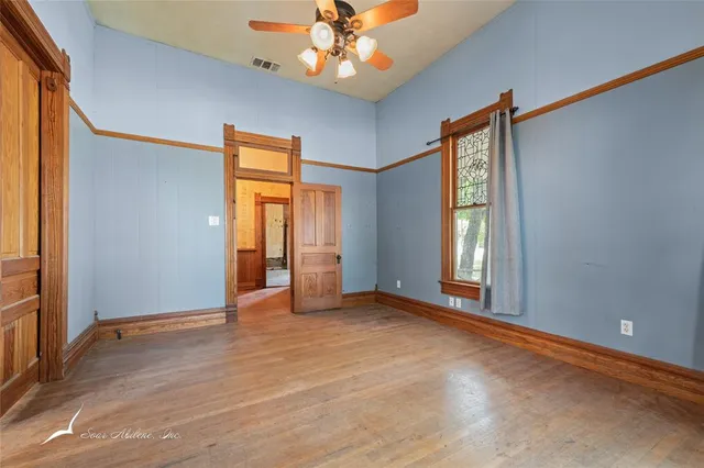 a view of an empty room with window and wooden floor