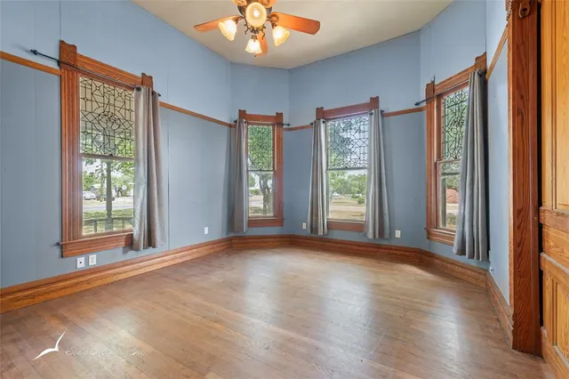 a view of an empty room with a window and wooden floor