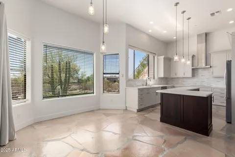 a large kitchen with kitchen island granite countertop a large window and white stainless steel appliances