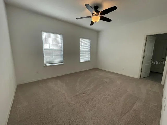 an empty room with windows and fan