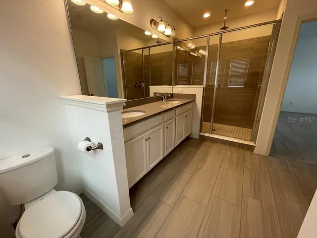a bathroom with a sink a toilet a mirror and shower
