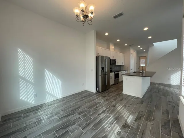 a view of a kitchen with stainless steel appliances granite countertop a refrigerator a stove and a wooden floors