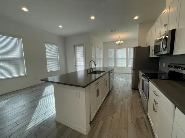 a kitchen with stainless steel appliances granite countertop a sink a stove and a wooden floors