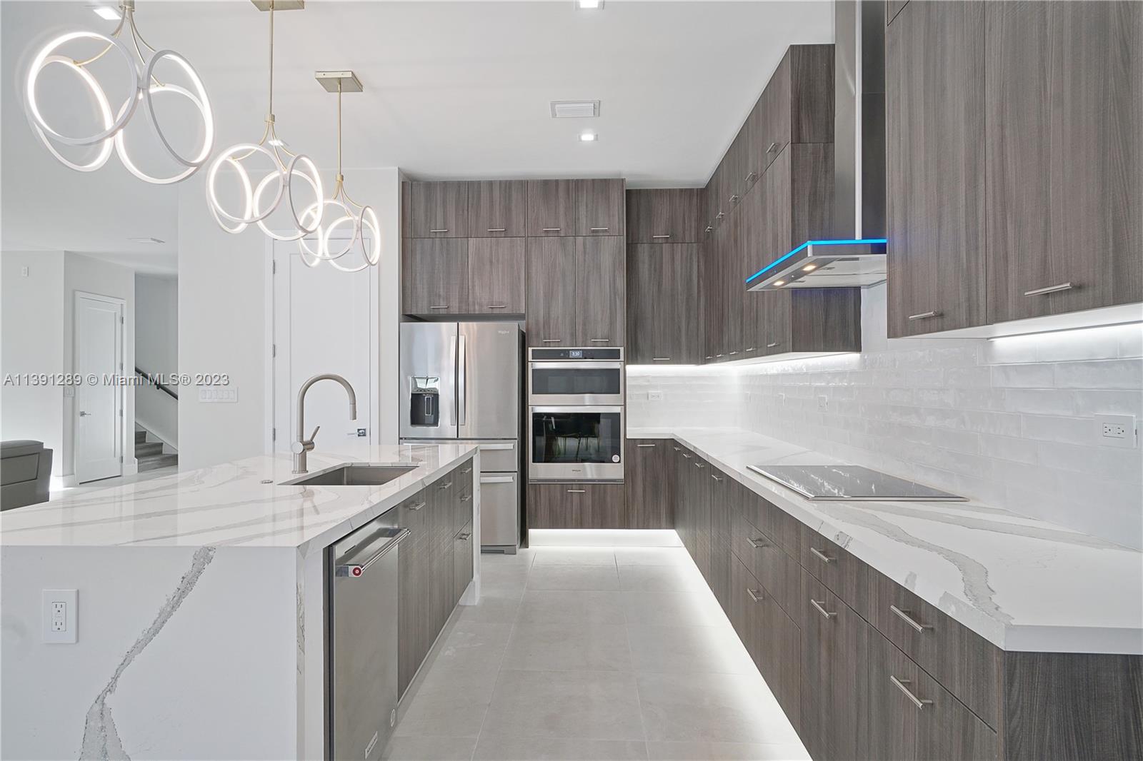 8096 Northwest 48th Terrace Doral, FL 33166 - Photo 22 of 28 a kitchen with kitchen island granite countertop a sink stainless steel appliances and cabinets