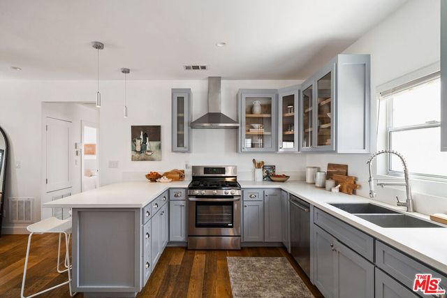 a kitchen with stainless steel appliances a refrigerator a stove a sink dishwasher a oven with white cabinets and wooden floor