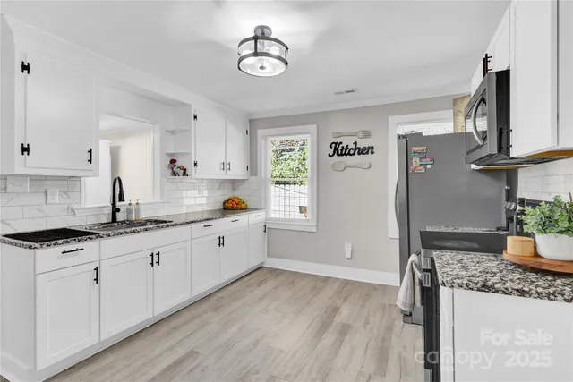 a kitchen with granite countertop a stove a sink and a refrigerator