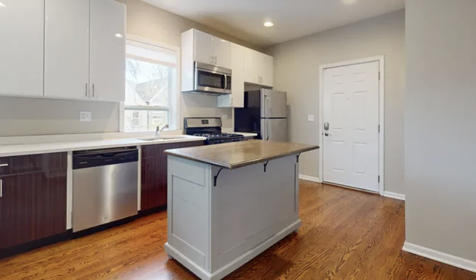 2101 West Fletcher Street, Unit 2F Chicago, IL 60618 - Photo 2 of 8 a kitchen with kitchen island granite countertop a sink cabinets and stainless steel appliances