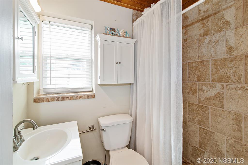 405 Tide Street New Smyrna Beach, FL 32169 - Photo 15 of 33 a bathroom with a toilet sink and mirror