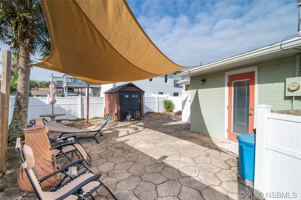 405 Tide Street New Smyrna Beach, FL 32169 - Photo 24 of 33 a view of a patio with a table and chairs under an umbrella