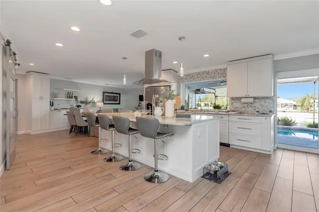 a large kitchen with stainless steel appliances kitchen island a large counter top a stove and a refrigerator