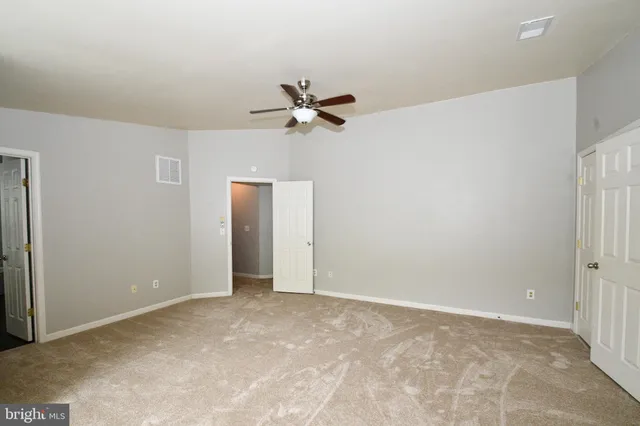 an empty room with closet and a ceiling fan
