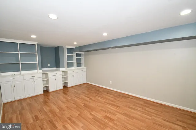 a view of an empty room with wooden floor and cabinet