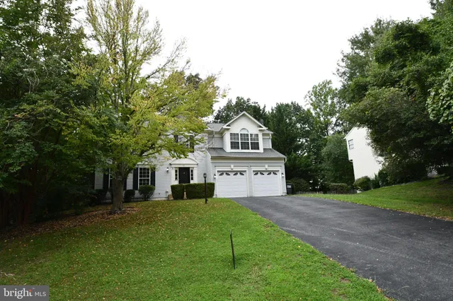 a view of house in front of a big yard with large trees