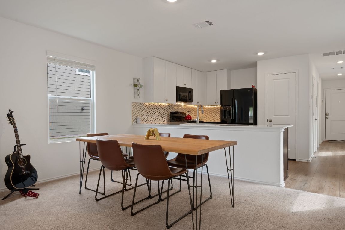 68 Trinity Circle Lockhart, TX 78644 - Photo 10 of 27 a kitchen with stainless steel appliances granite countertop a sink a stove a refrigerator cabinets and a dining table with wooden floor