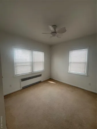 an empty room with windows and ceiling fan