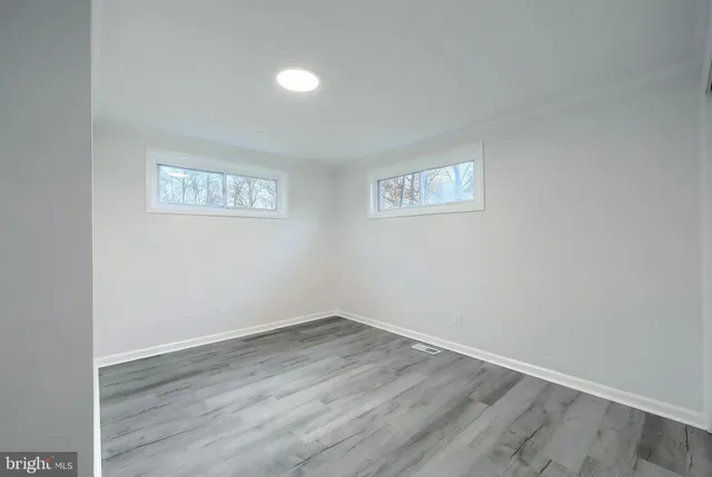 an empty room with wooden floor and window