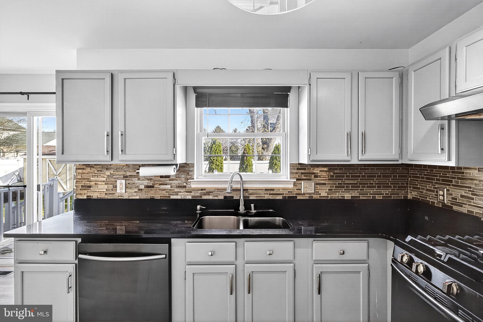 221 Romeo Drive New Castle, DE 19720 - Photo 20 of 38 a kitchen with granite countertop a sink a stove and cabinets