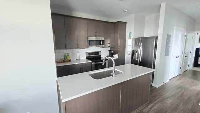 a kitchen with a refrigerator a stove and a sink with wooden floor