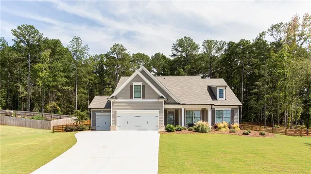 a view of a house with yard and trees in the background