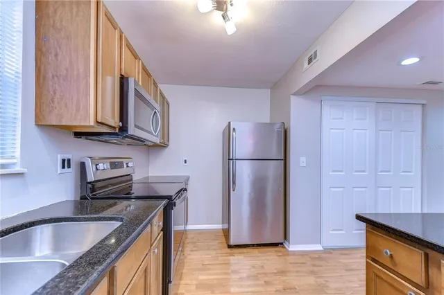 a kitchen with stainless steel appliances granite countertop a refrigerator a sink a stove a counter space and cabinets