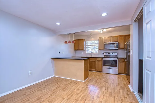 a kitchen with stainless steel appliances granite countertop a stove a sink and a refrigerator with wooden floor