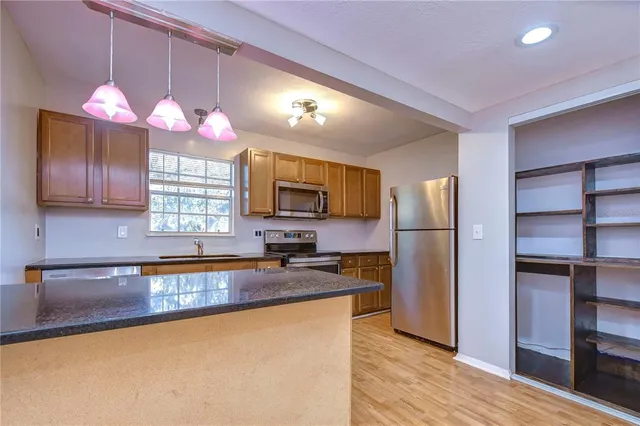 a kitchen with granite countertop a sink cabinets and stainless steel appliances