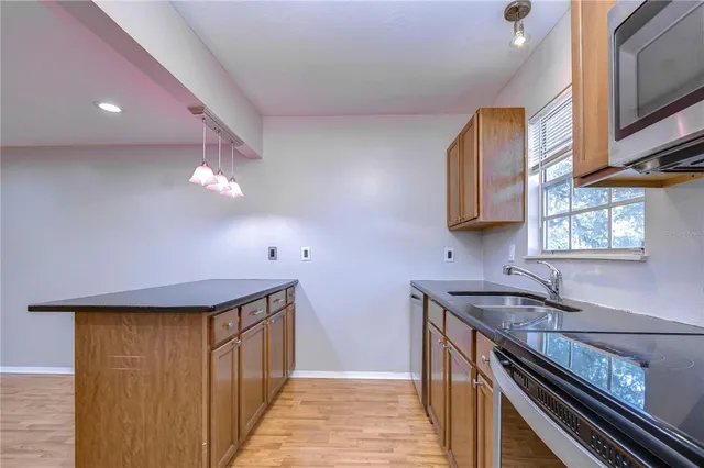 a kitchen with stainless steel appliances a sink dishwasher a stove a microwave oven with cabinets and wooden floor