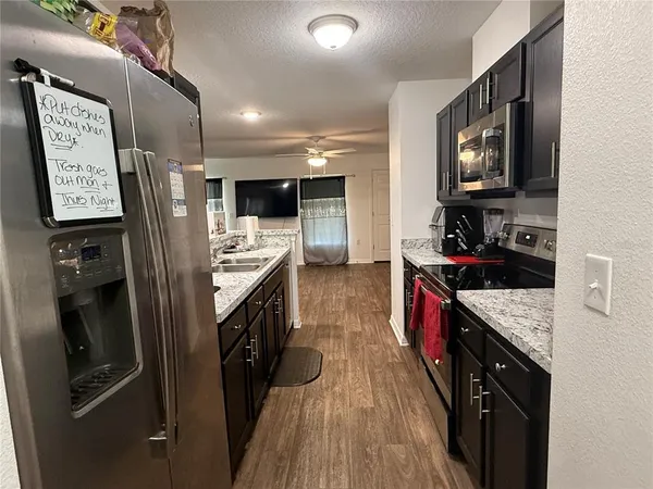a kitchen with stainless steel appliances granite countertop a refrigerator a stove top oven a sink and dishwasher