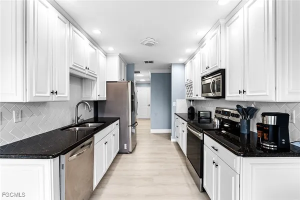 a kitchen with kitchen island granite countertop a sink appliances cabinets and a counter top space