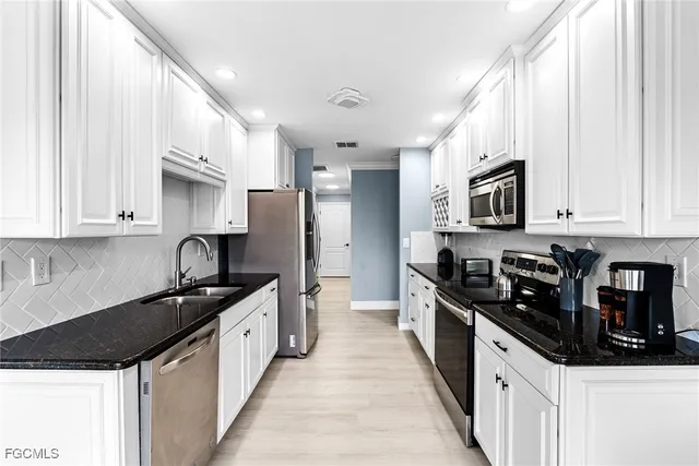 a kitchen with kitchen island granite countertop a sink appliances cabinets and a counter top space