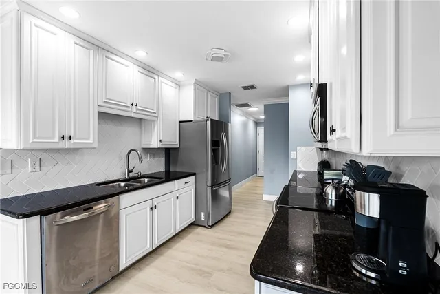 a kitchen with granite countertop white cabinets and stainless steel appliances