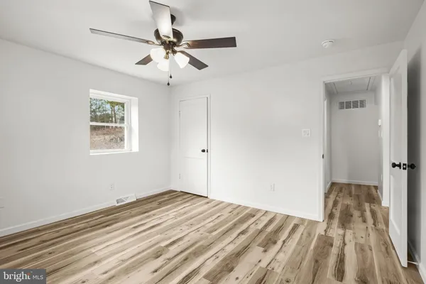a view of a bedroom with wooden floor and a ceiling fan