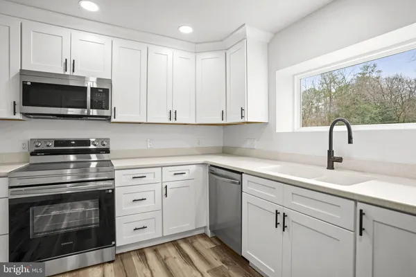 a kitchen with white cabinets stainless steel appliances and sink