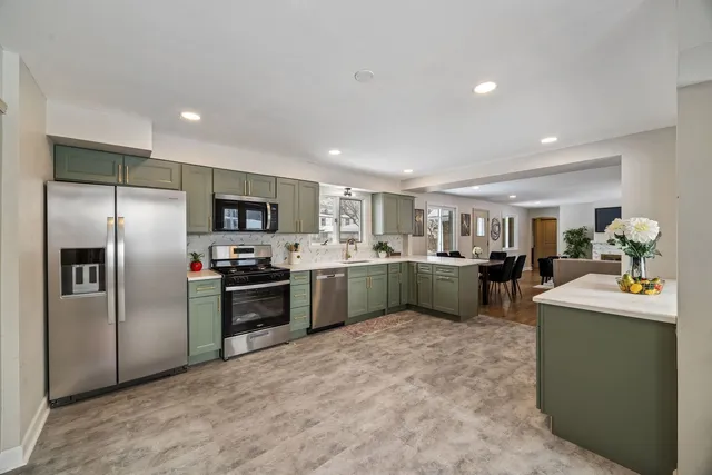 a kitchen with kitchen island a counter top space stainless steel appliances and cabinets