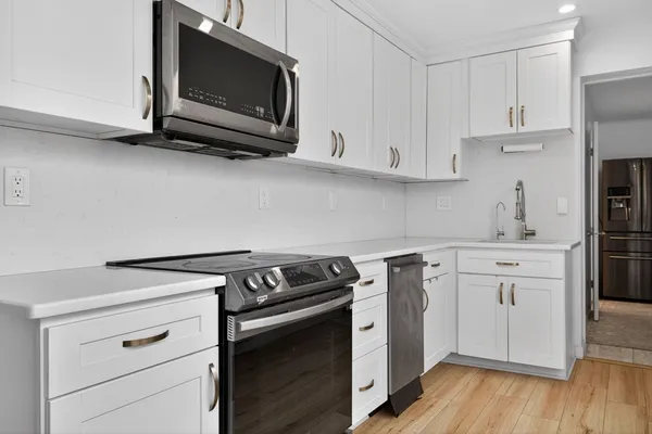a kitchen with white cabinets stainless steel appliances and wooden floor