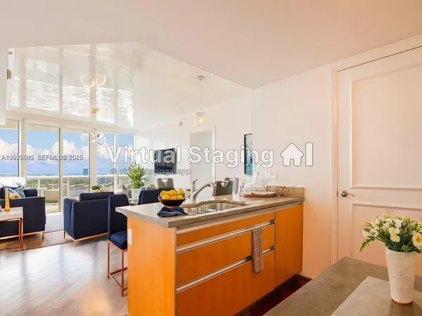 a dining room with furniture a rug and kitchen view