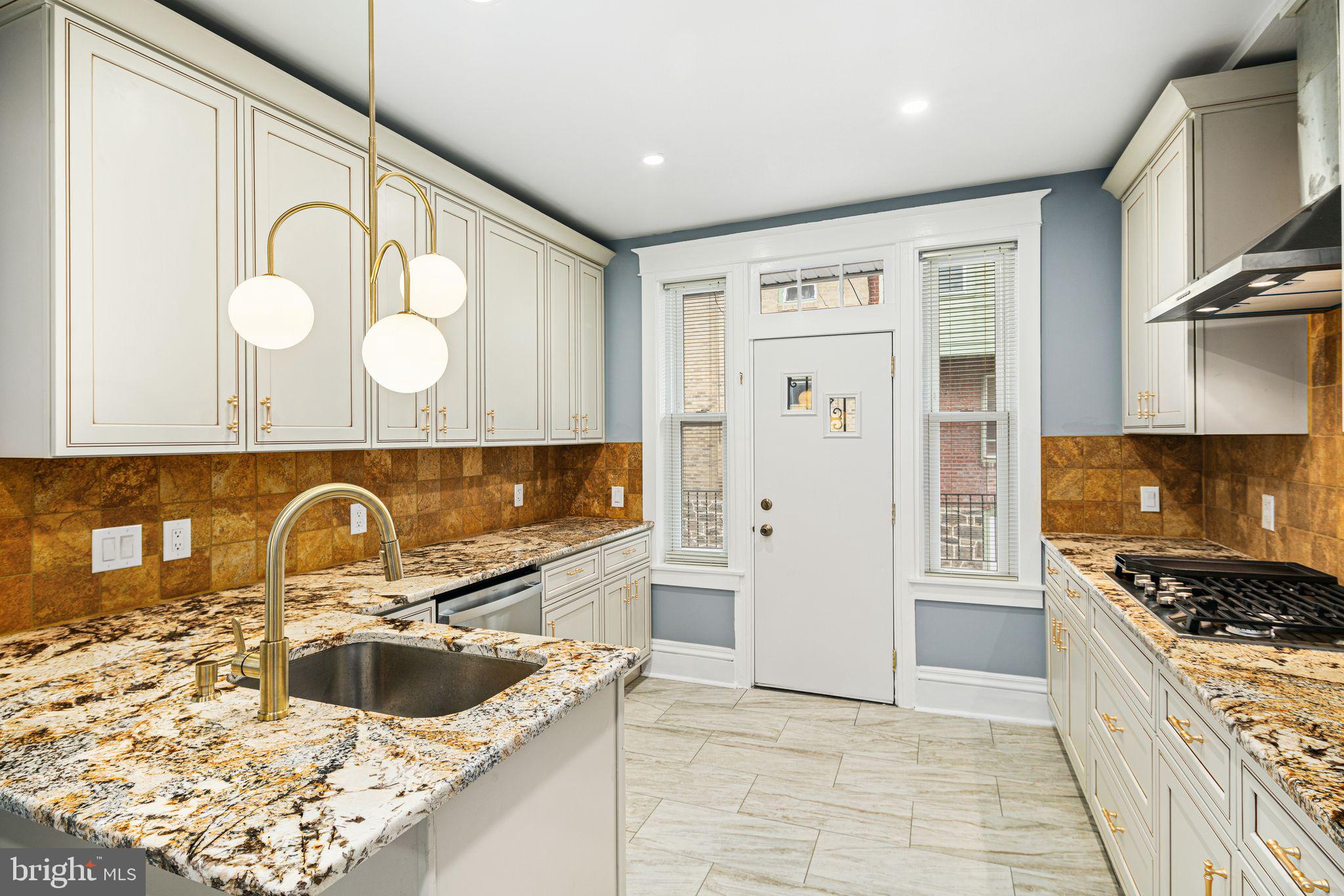 452 South 48th Street Philadelphia, PA 19143 - Photo 12 of 60 a kitchen with granite countertop a sink and a stove top oven with wooden floor