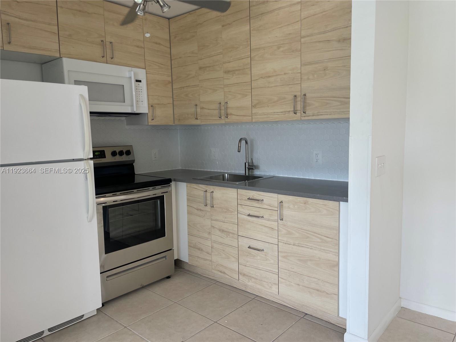 119 Tilford F, Unit 119 Deerfield Beach, FL 33442 - Photo 13 of 36 a kitchen with white cabinets and white appliances