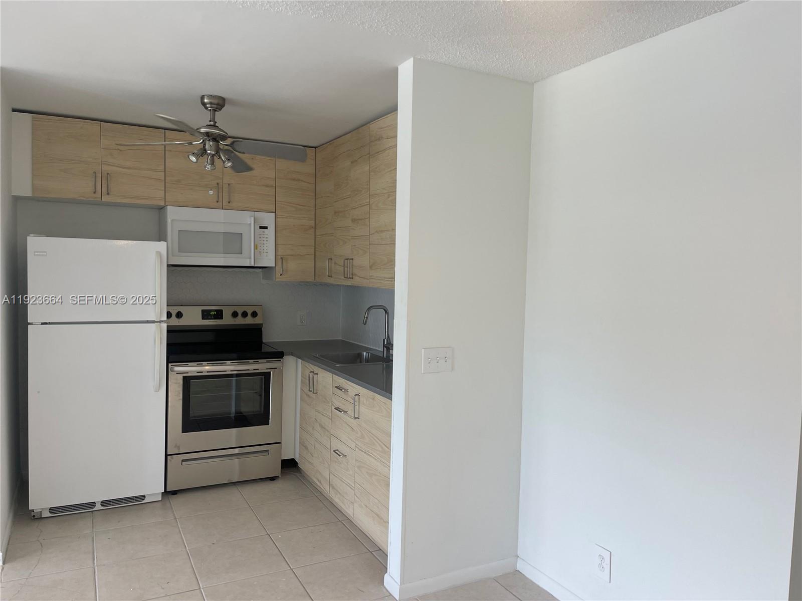 119 Tilford F, Unit 119 Deerfield Beach, FL 33442 - Photo 14 of 36 a kitchen with a refrigerator and white cabinets
