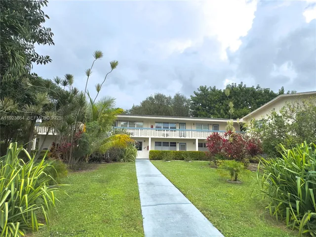 a view of house with garden and tall trees