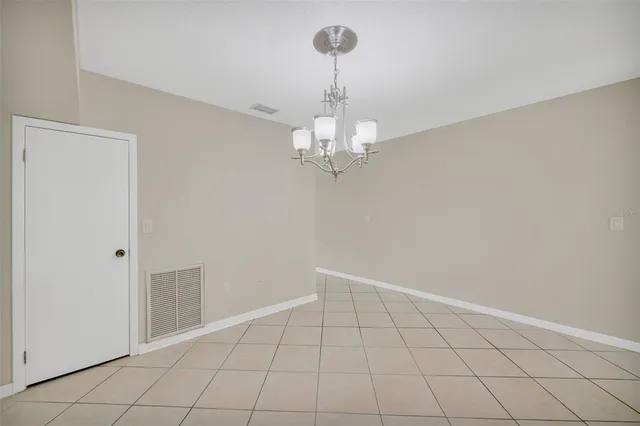 a view of an empty room with chandelier fan