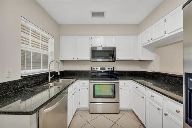 a kitchen with stainless steel appliances granite countertop a sink stove and cabinets
